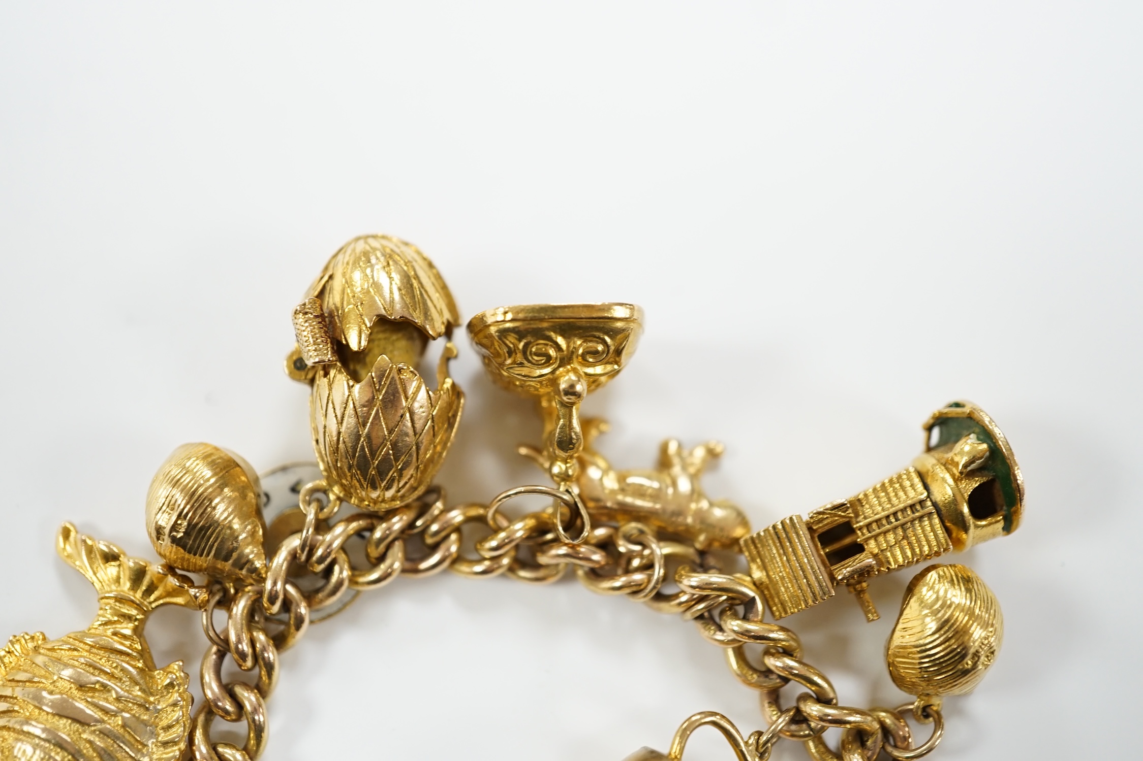 A 9ct gold curb link charm bracelet, with heart shaped padlock clasp and hung with assorted mainly 9ct gold charms